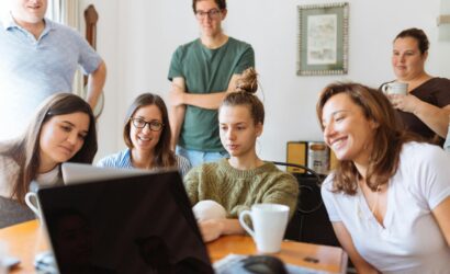 A diverse group of adults at work, enjoying a casual meeting indoors with focus and smiles.