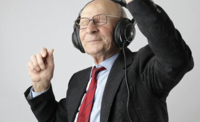 Senior man enjoying music with headphones, expressing happiness and energy.