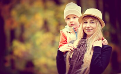 A joyful mother and child in warm hats, enjoying a sunny autumn day outdoors.
