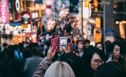 Vibrant street scene in a busy city market with diverse crowds and bright neon signage.