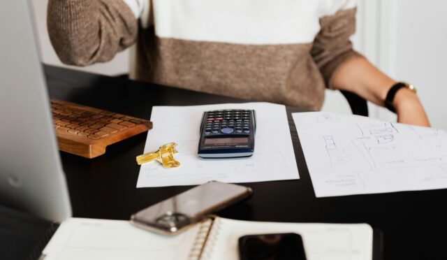 A business desk setup with a calculator, papers, and a keyboard, reflecting a work environment.