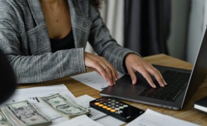 A businesswoman working on finance management with cash and calculator on desk.
