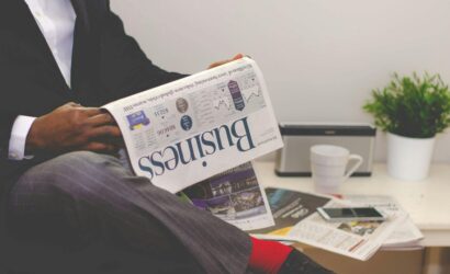 Businessman reading a financial newspaper at a desk, highlighting finance and commerce theme.