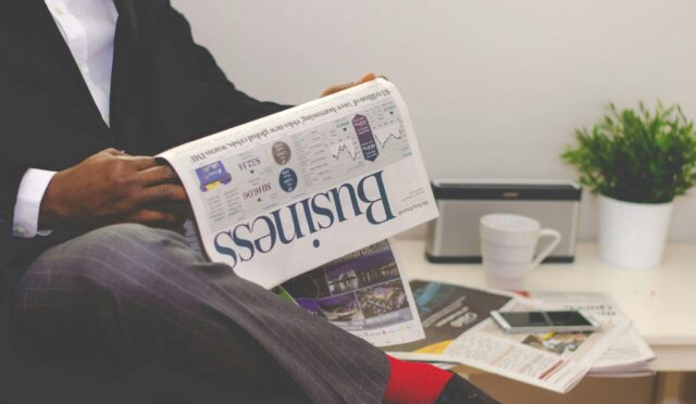 Businessman reading a financial newspaper at a desk, highlighting finance and commerce theme.