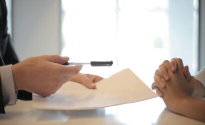 Close-up of a contract signing with hands over documents. Professional business interaction.