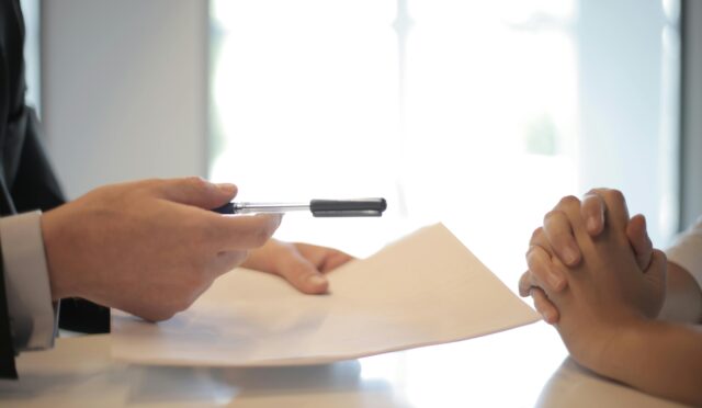 Close-up of a contract signing with hands over documents. Professional business interaction.