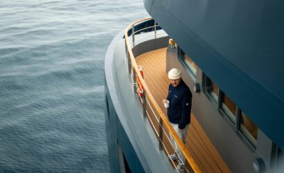 Man enjoys coffee on yacht deck overlooking the serene sea, providing a sense of adventure and relaxation.