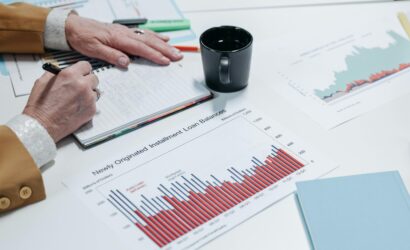 Close-up of a person analyzing financial charts and taking notes in an office setting.